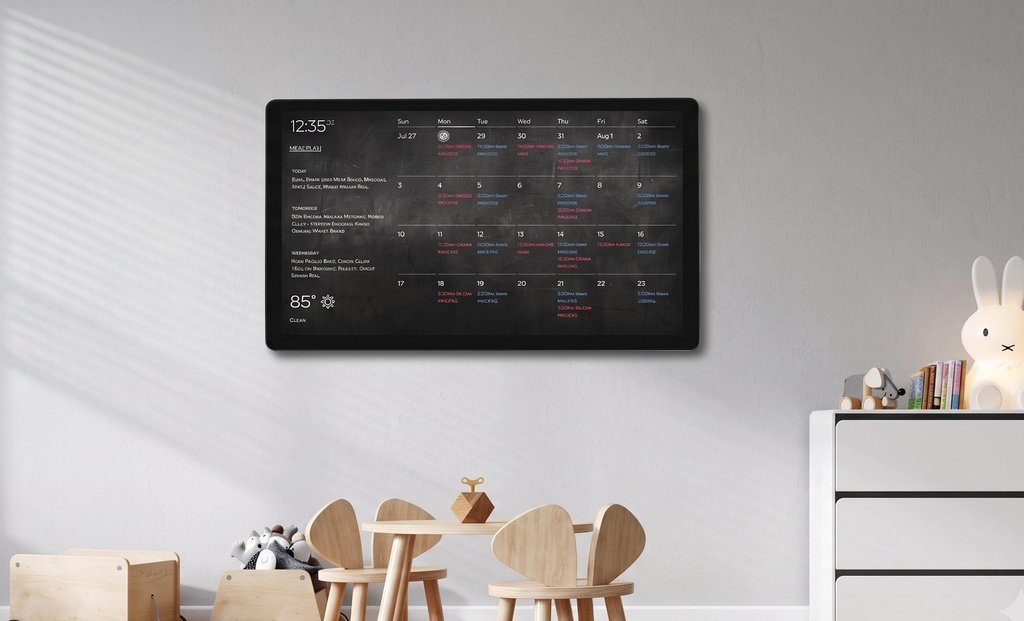 Landscape wall-mounted DAKboard in a child's playroom showing a monthly meal-plan calendar with dinner ideas listed for each day