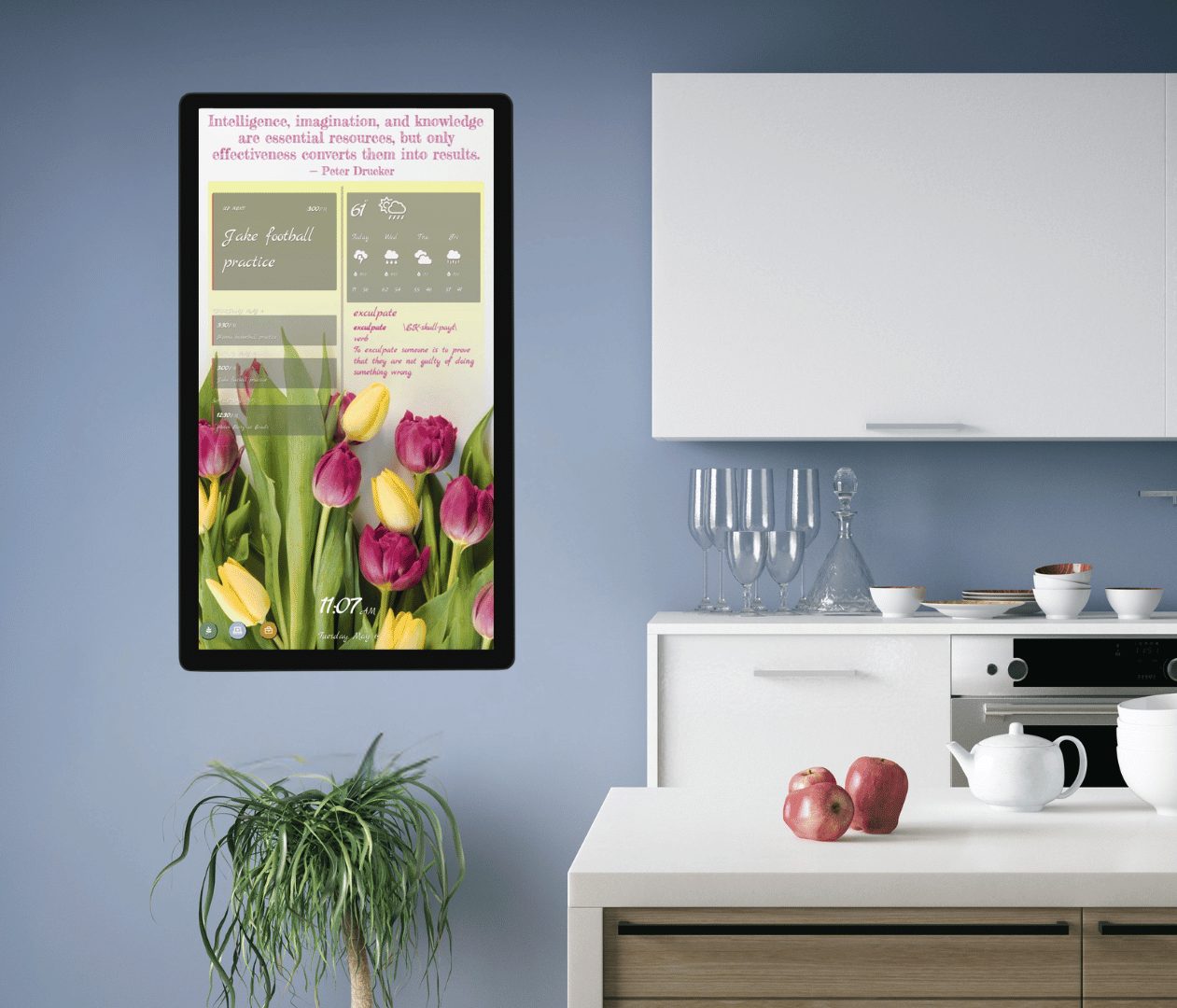 DAKboard Wall Display A portrait DAKboard Wall Display mounted in a kitchen shows a daily inspirational quote, the upcoming schedule, a weather forecast, and a full-screen tulip photo