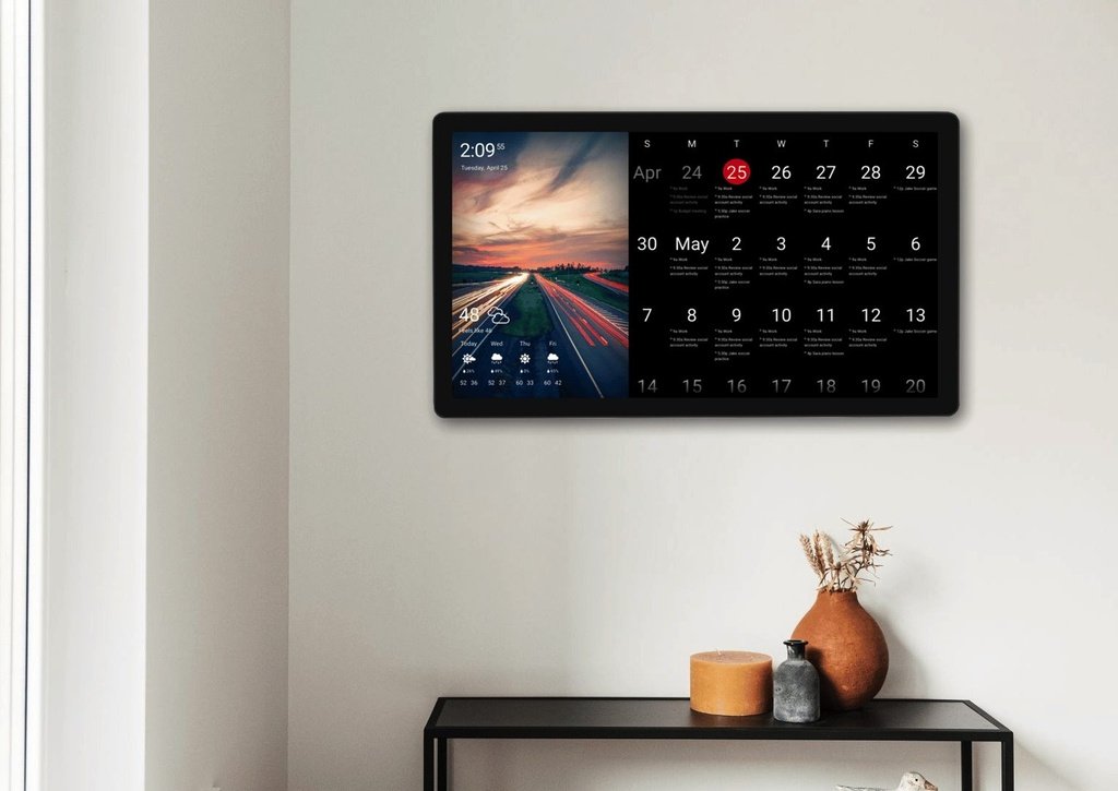 Readable family calendar Wall-mounted DAKboard showing a monthly family calendar beside a highway sunset photo with a five-day weather forecast