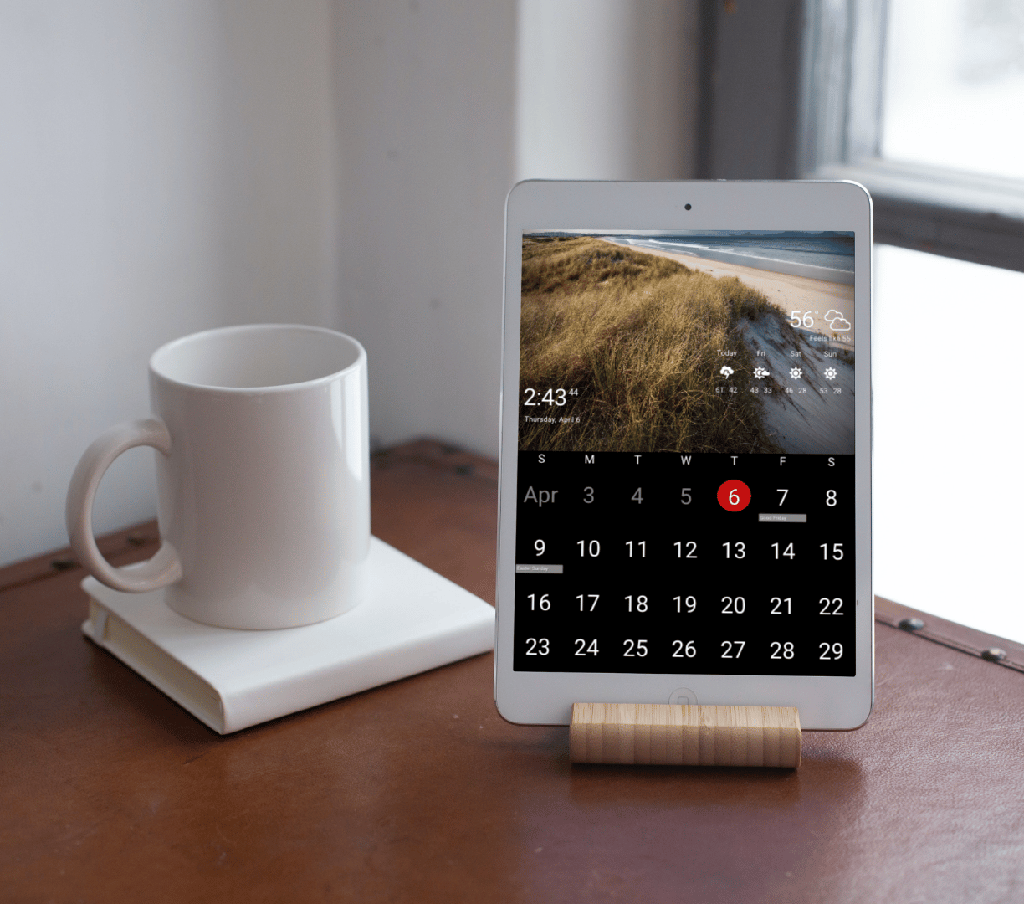 iPad running DAKboard An iPad on a small wooden stand running DAKboard's calendar and weather beside a coffee mug on a desk
