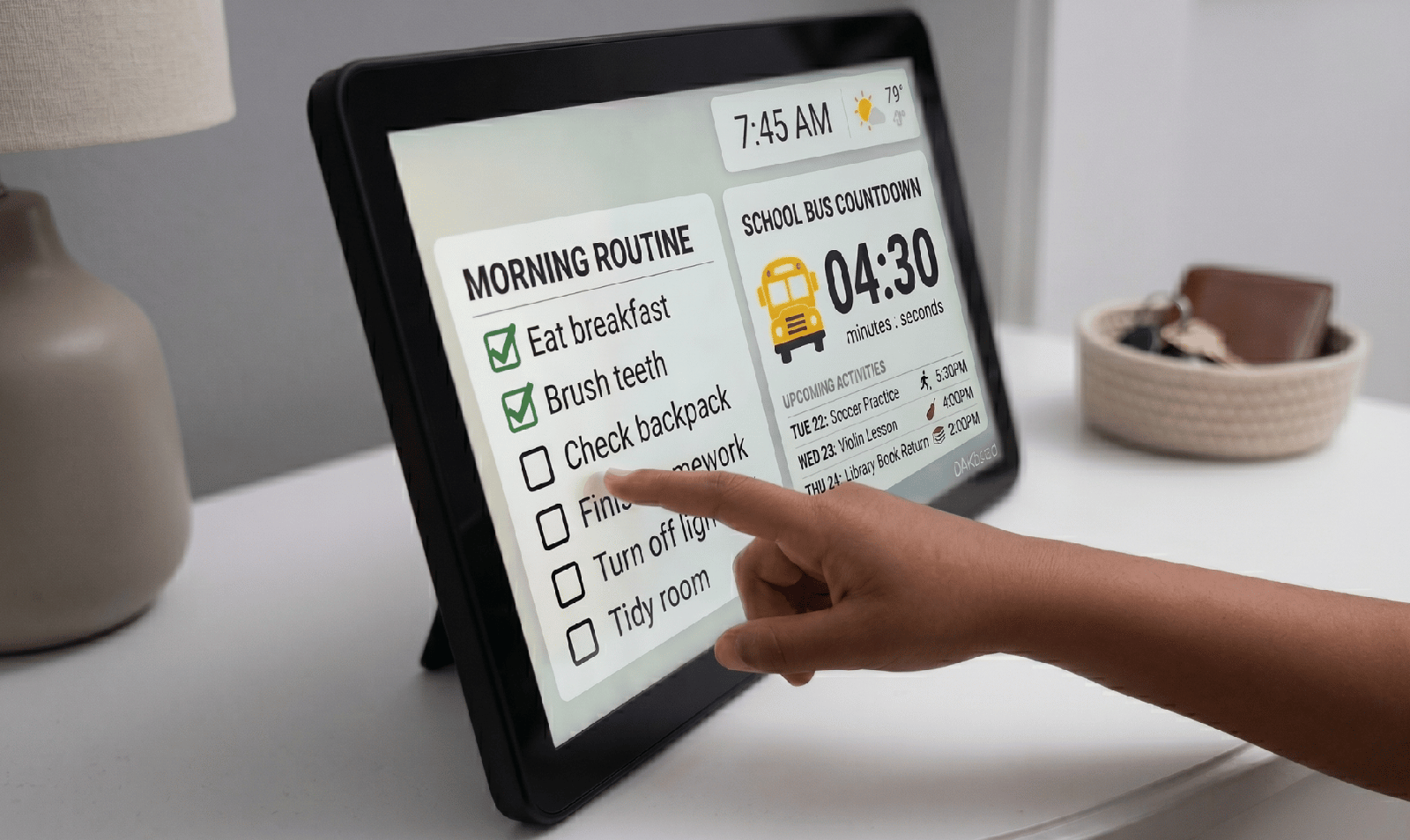 Kids routine touchscreen A child taps a DAKboard tablet showing a morning-routine checklist and a live school-bus countdown timer