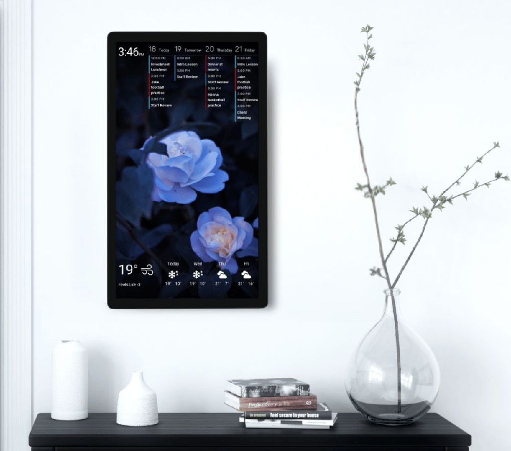 DAKboard wall display Portrait wall-mounted DAKboard touchscreen showing a four-day agenda and weather forecast over a blue floral background